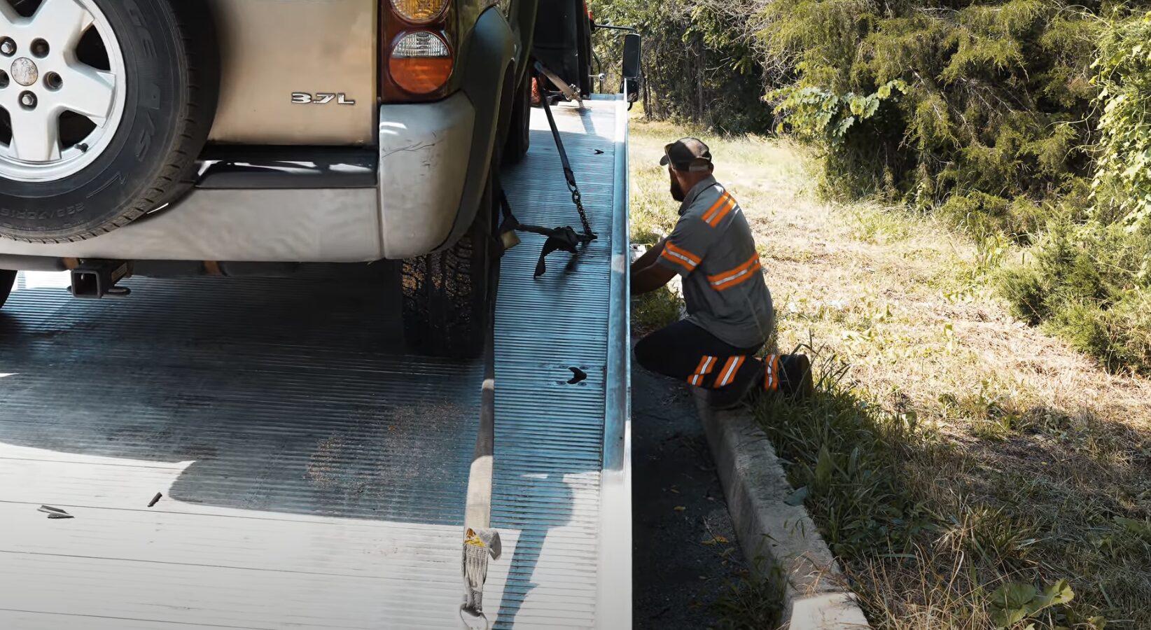 Professional tow truck operator securing vehicle on flatbed
